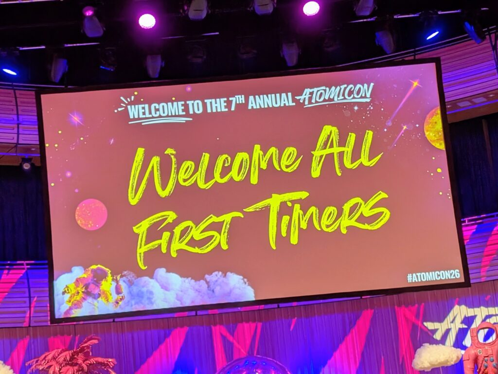 Atomicon brightly coloured screen that says Welcome All First Timers