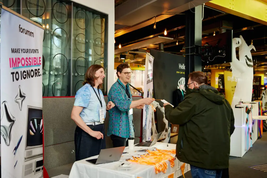 Two people at a desk handing out a badge to an attendee